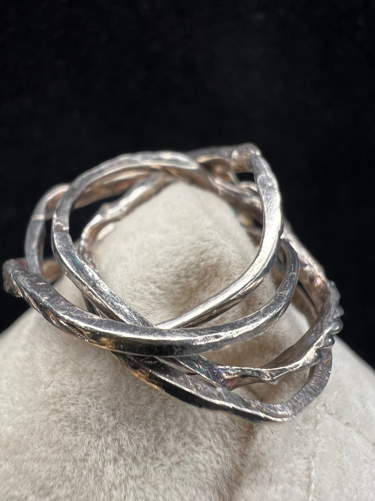 This sterling silver flower ring features four interconnected bands, creating a distinctive and elegant twist on a classic design.