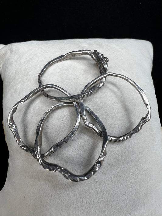 This sterling silver flower ring features four interconnected bands, creating a distinctive and elegant twist on a classic design.