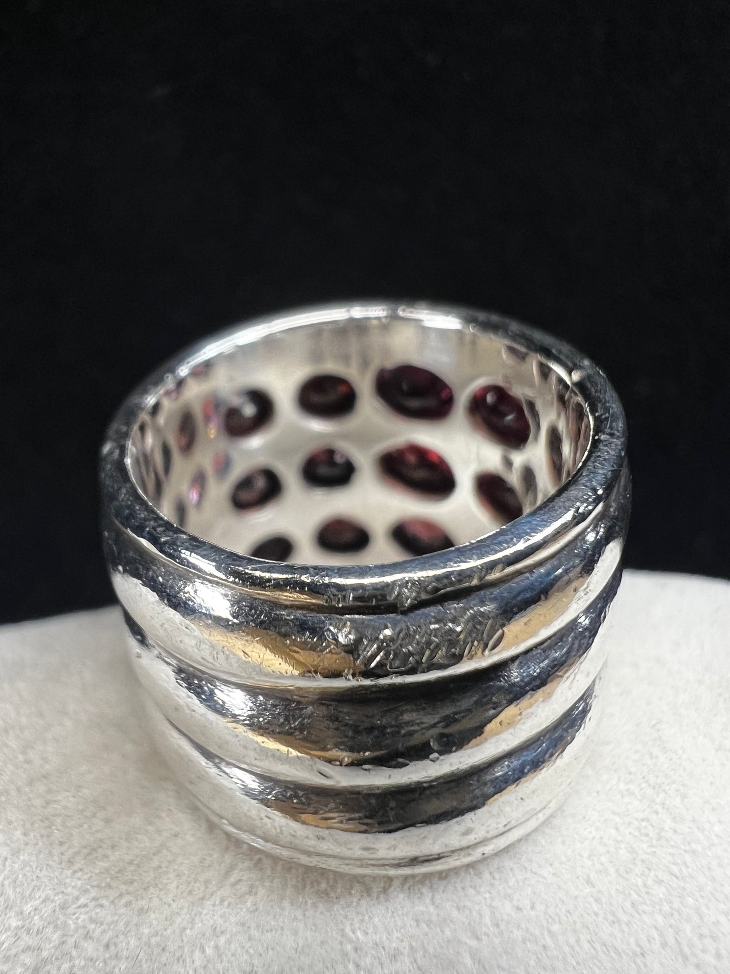 This striking vintage sterling silver ring features 12 garnets with a subtle purple tint, creating a bold and elegant statement piece. Please note that the ring has some scuffs, including a larger mark on the back, which you can see in the photos.