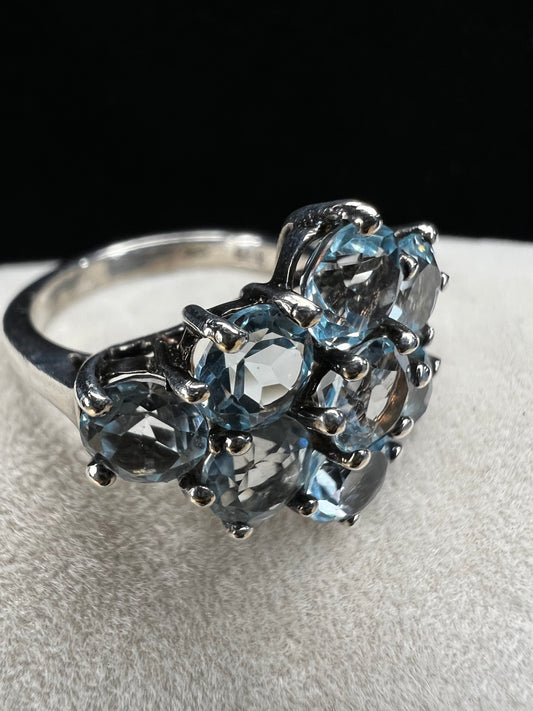 This sterling silver ring, adorned with nine sparkling light blue topaz stones, offers a delicate and elegant touch to any outfit.