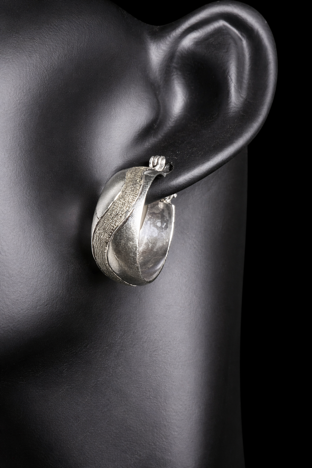 This vintage pair of sterling silver hoop earrings feature an etched design that resembles a snake wrapping around each earring.