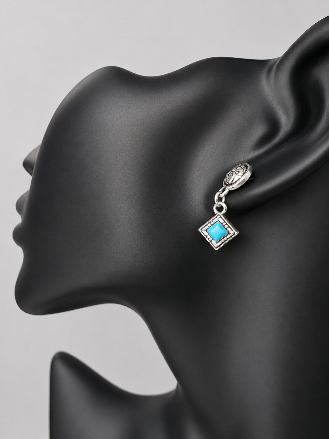 Here are handcrafted sterling silver dangle earrings inspired by native design aesthetics, featuring turquoise accents that swing with natural grace. The intricate silverwork combines traditional artistry with contemporary style, making these earrings a versatile statement piece.