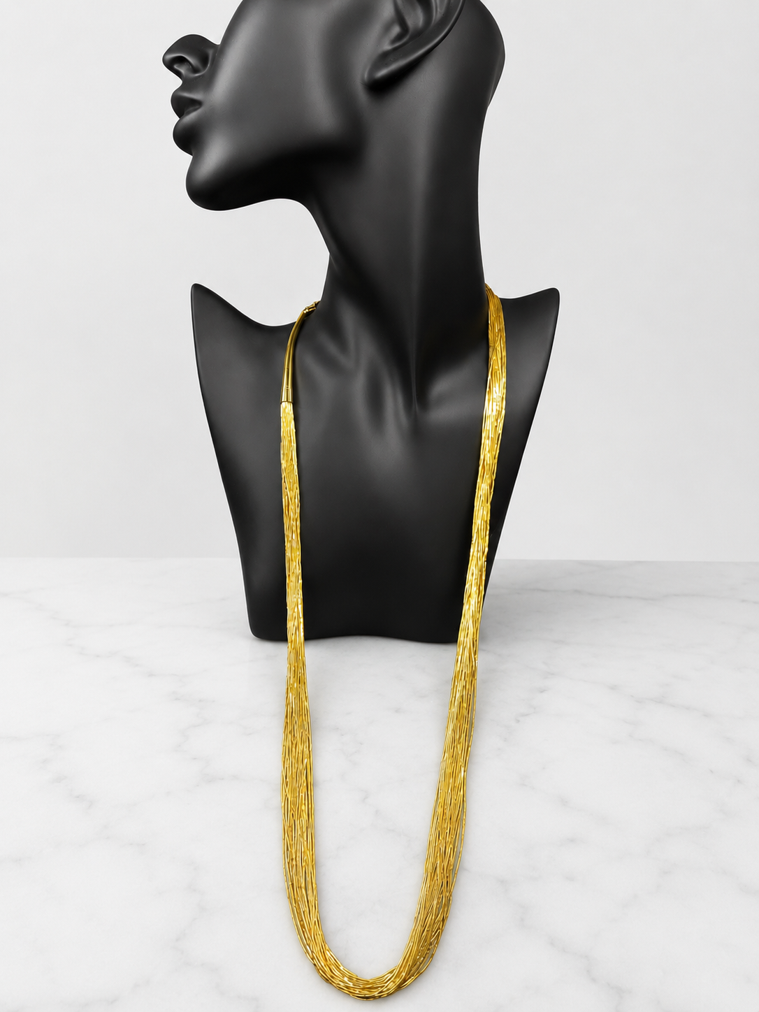 This is a striking gold over sterling silver necklace, featuring the iconic liquid-sterling design. The fluid, sculptural form creates visual movement and dimension, while the gold overlay adds warmth and luxury to the cool brilliance of sterling silver. With substantial length and thickness, this piece commands attention as a standalone statement.