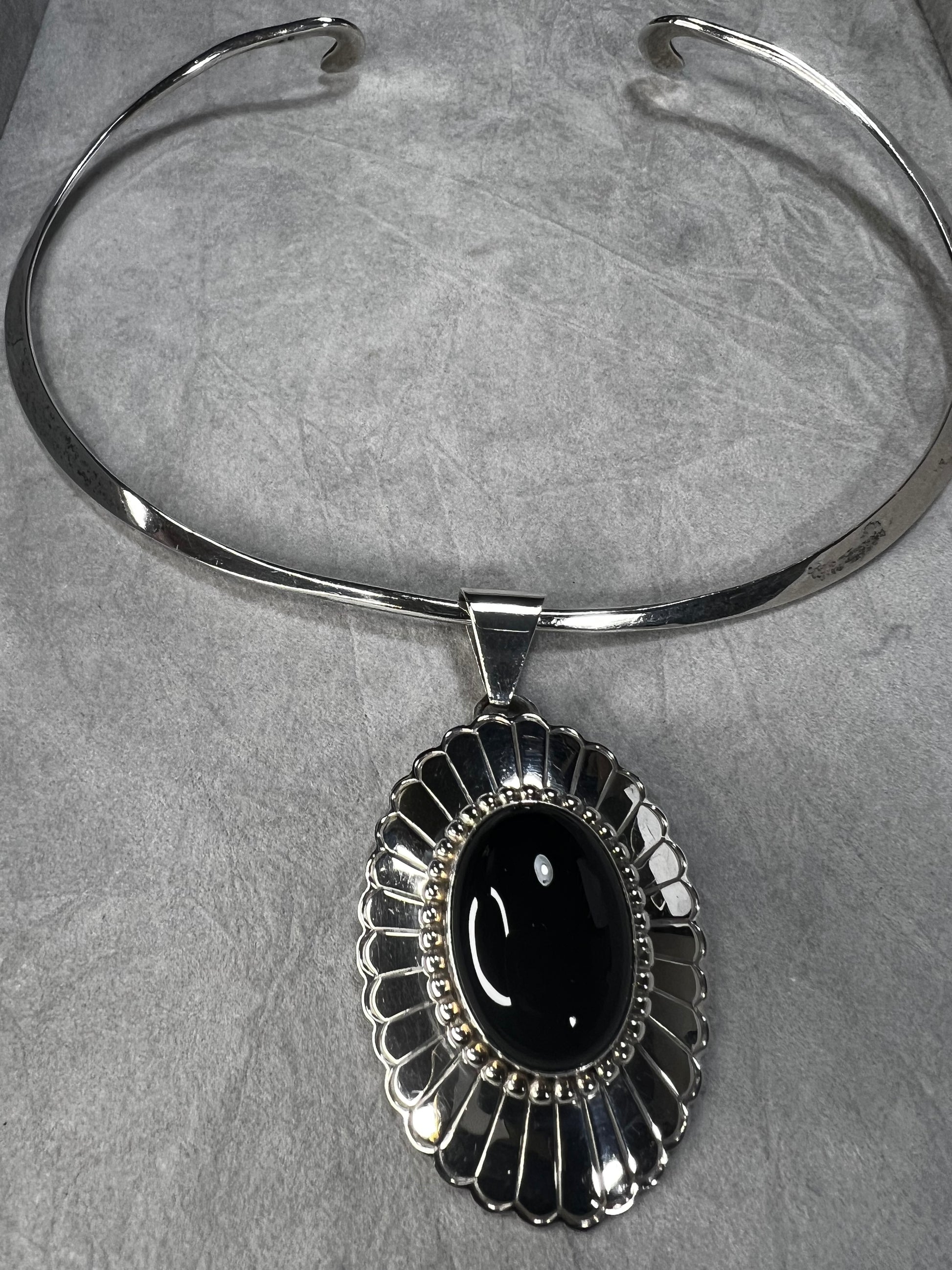 This slide pendant necklace features a large onyx and sterling pendant front and center with a sterling collar. From native American silversmith L. James.