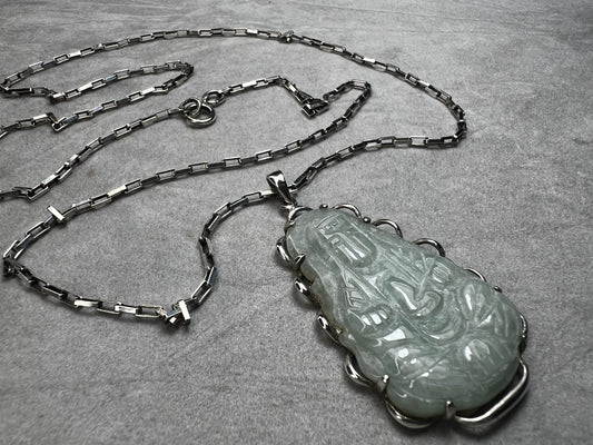 This vintage necklace combines the timeless elegance of sterling silver with the delicate beauty of a carved pastel green jade pendant. The sturdy rectangular link chain ensures durability while gracefully supporting the pendant.
