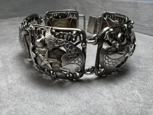 This vintage Denmark sterling silver bracelet, featuring charming fish and star motifs, is a rare find. Its unique design adds a touch of timeless elegance to any outfit, making it a special piece to treasure.