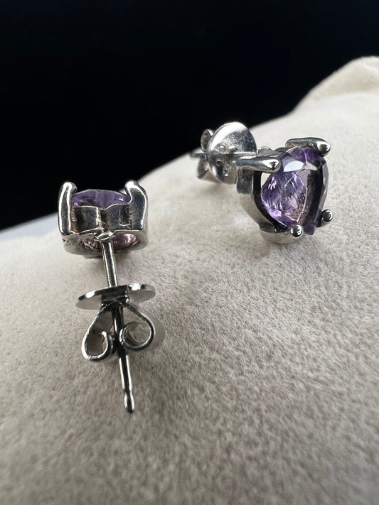These sterling silver earrings feature heart-shaped amethyst stones, expertly cut to showcase their natural beauty. The rich purple hues of the amethyst add a touch of elegance. Perfect for adding a subtle yet sophisticated accent to any outfit.
