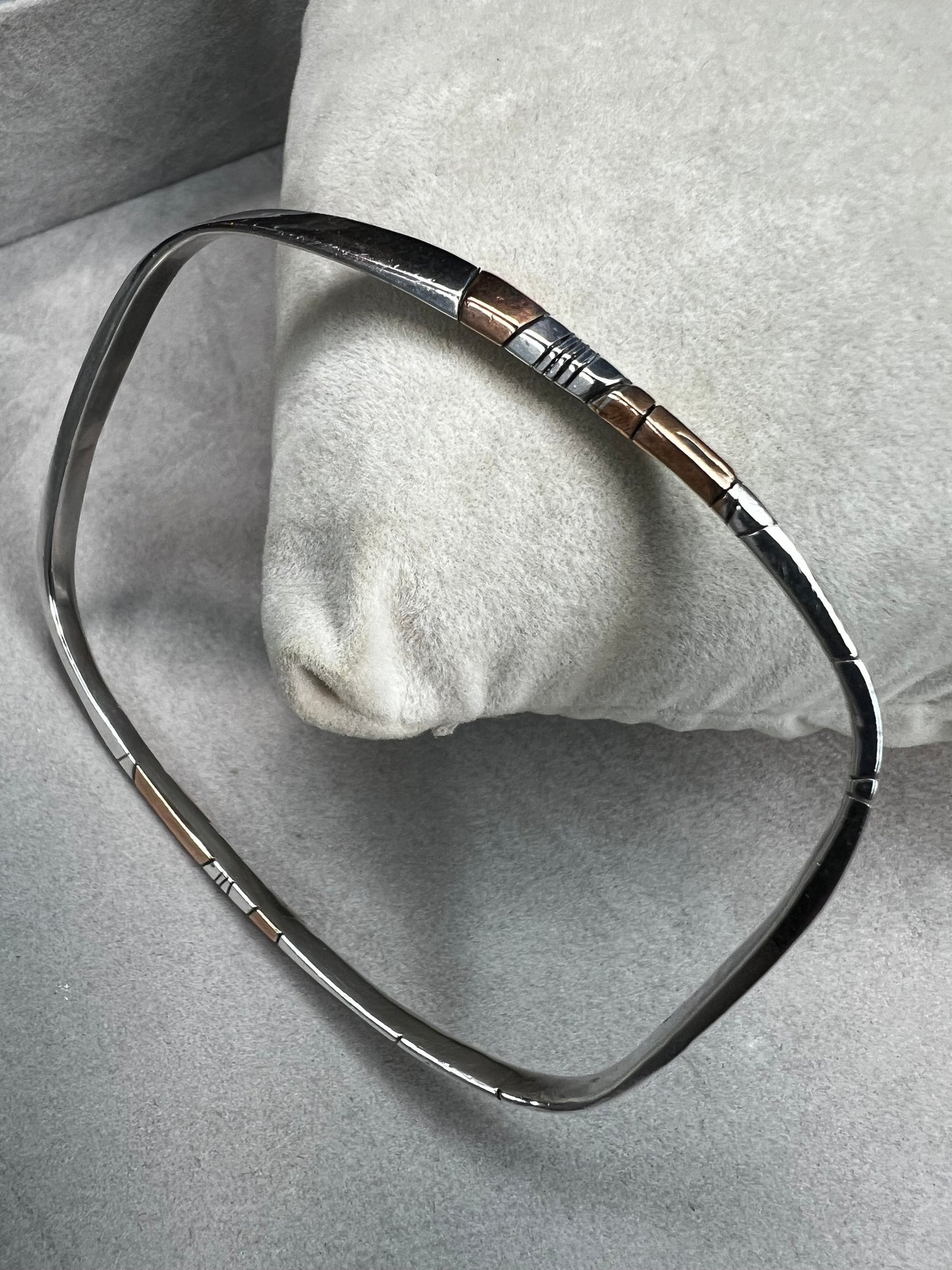 Here is an elegant vintage sterling silver bracelet featuring inlaid copper accents and hand-etched detailing. The distinctive rectangular design creates a modern yet timeless aesthetic, making this piece a standout addition to any jewelry collection.