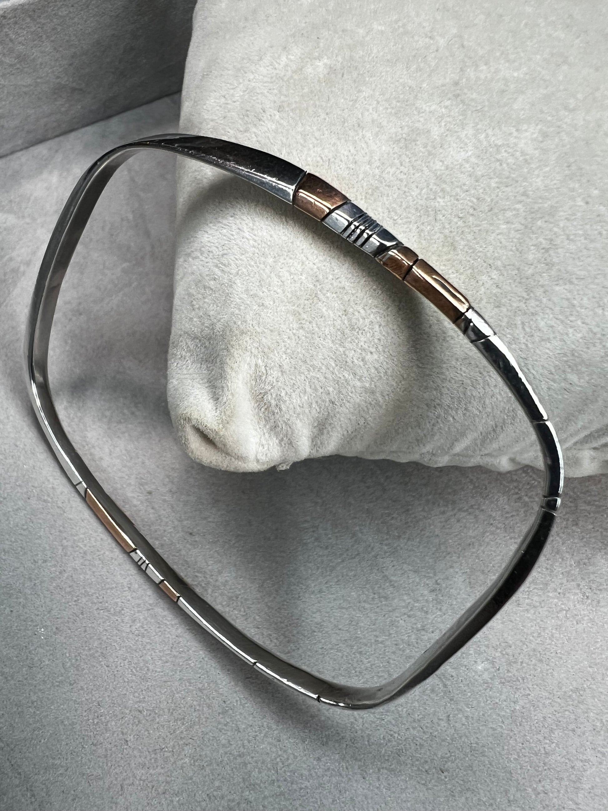 Here is an elegant vintage sterling silver bracelet featuring inlaid copper accents and hand-etched detailing. The distinctive rectangular design creates a modern yet timeless aesthetic, making this piece a standout addition to any jewelry collection.