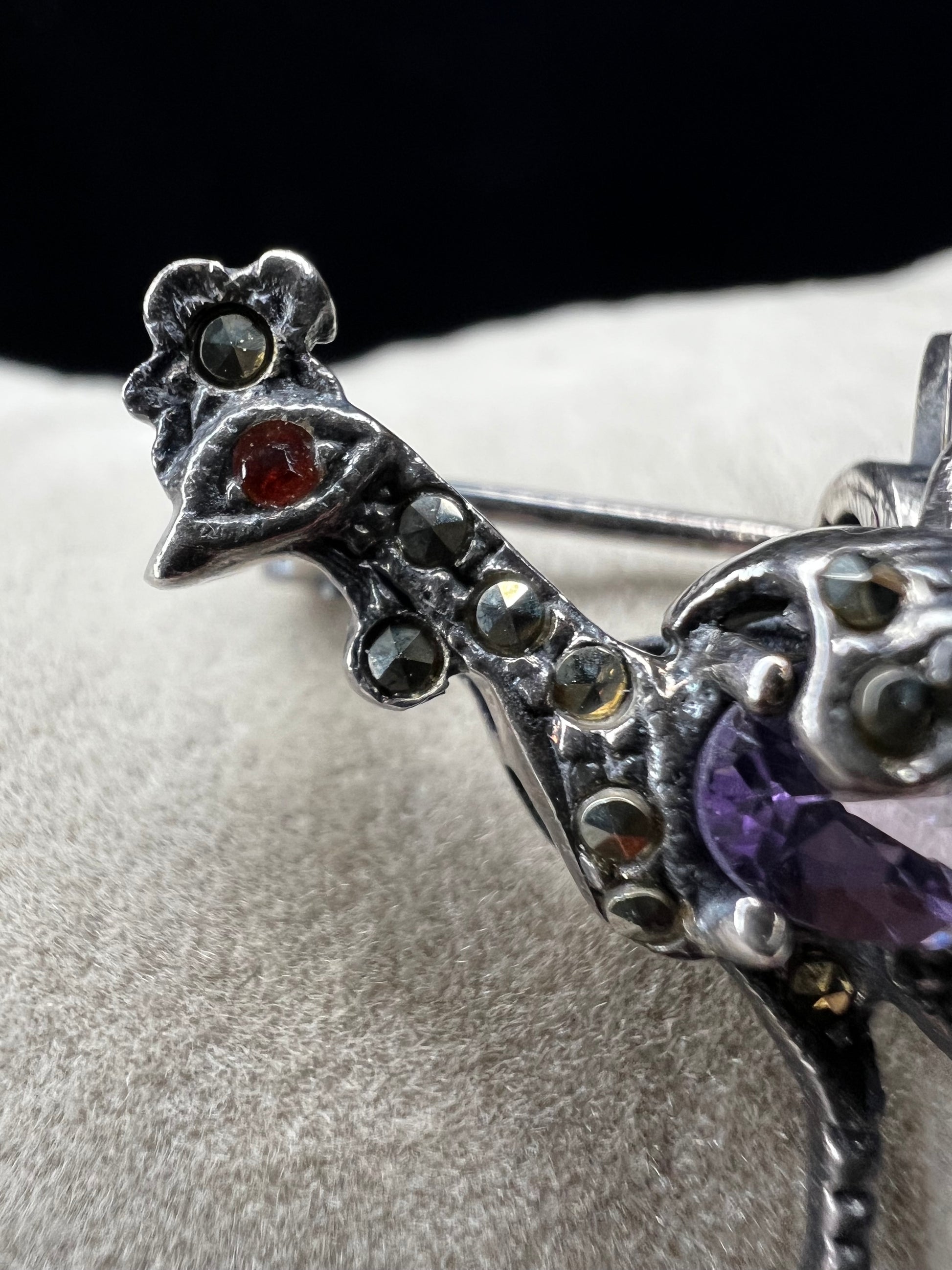This is a striking mid-century rooster brooch that captures vintage elegance and whimsy. Handcrafted in sterling silver, this statement piece features a vibrant amethyst belly, accented with shimmering marcasite details that catch the light. Perfect for adding character to any outfit or displaying as a collectible treasure.