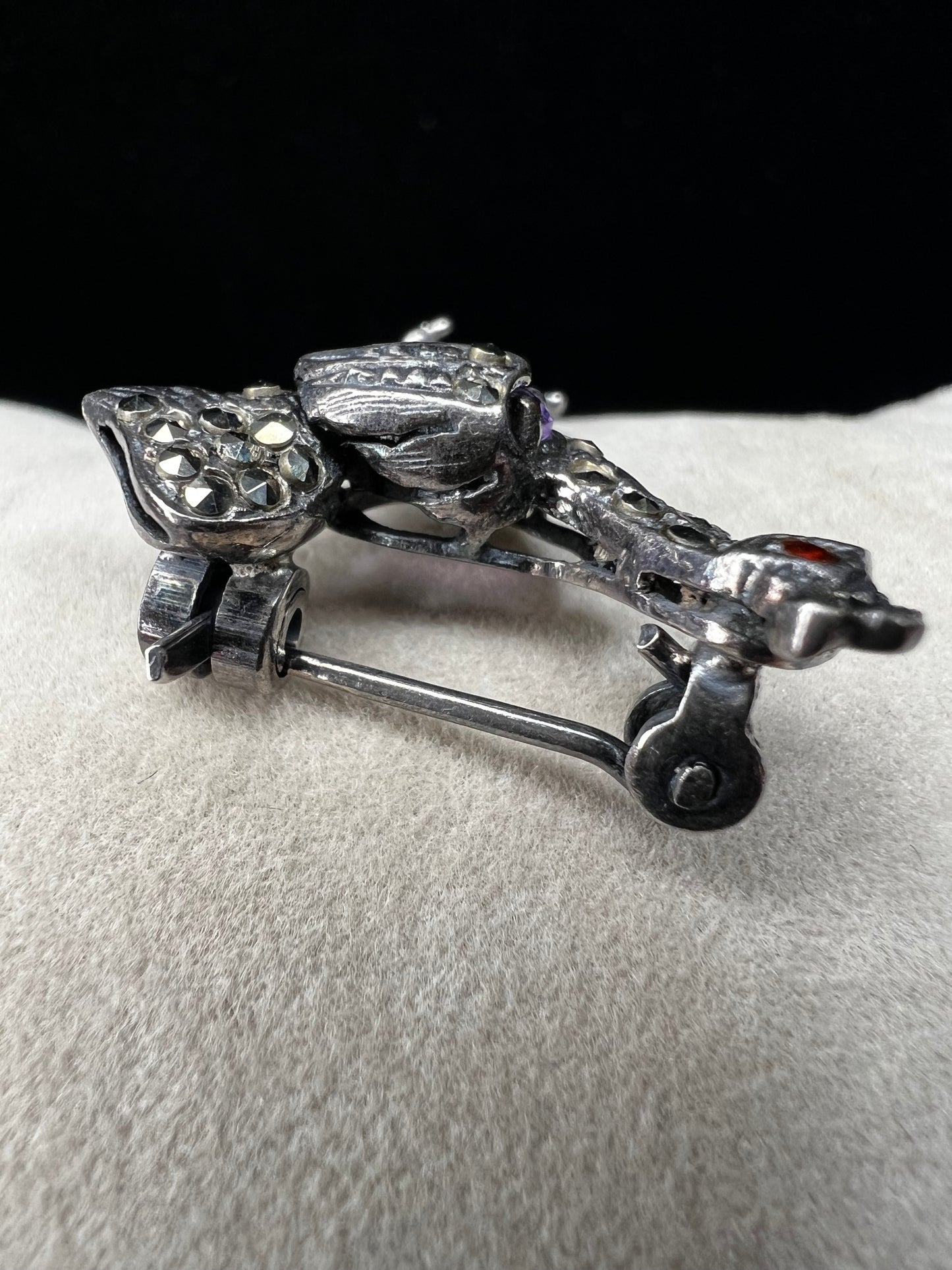 This is a striking mid-century rooster brooch that captures vintage elegance and whimsy. Handcrafted in sterling silver, this statement piece features a vibrant amethyst belly, accented with shimmering marcasite details that catch the light. Perfect for adding character to any outfit or displaying as a collectible treasure.