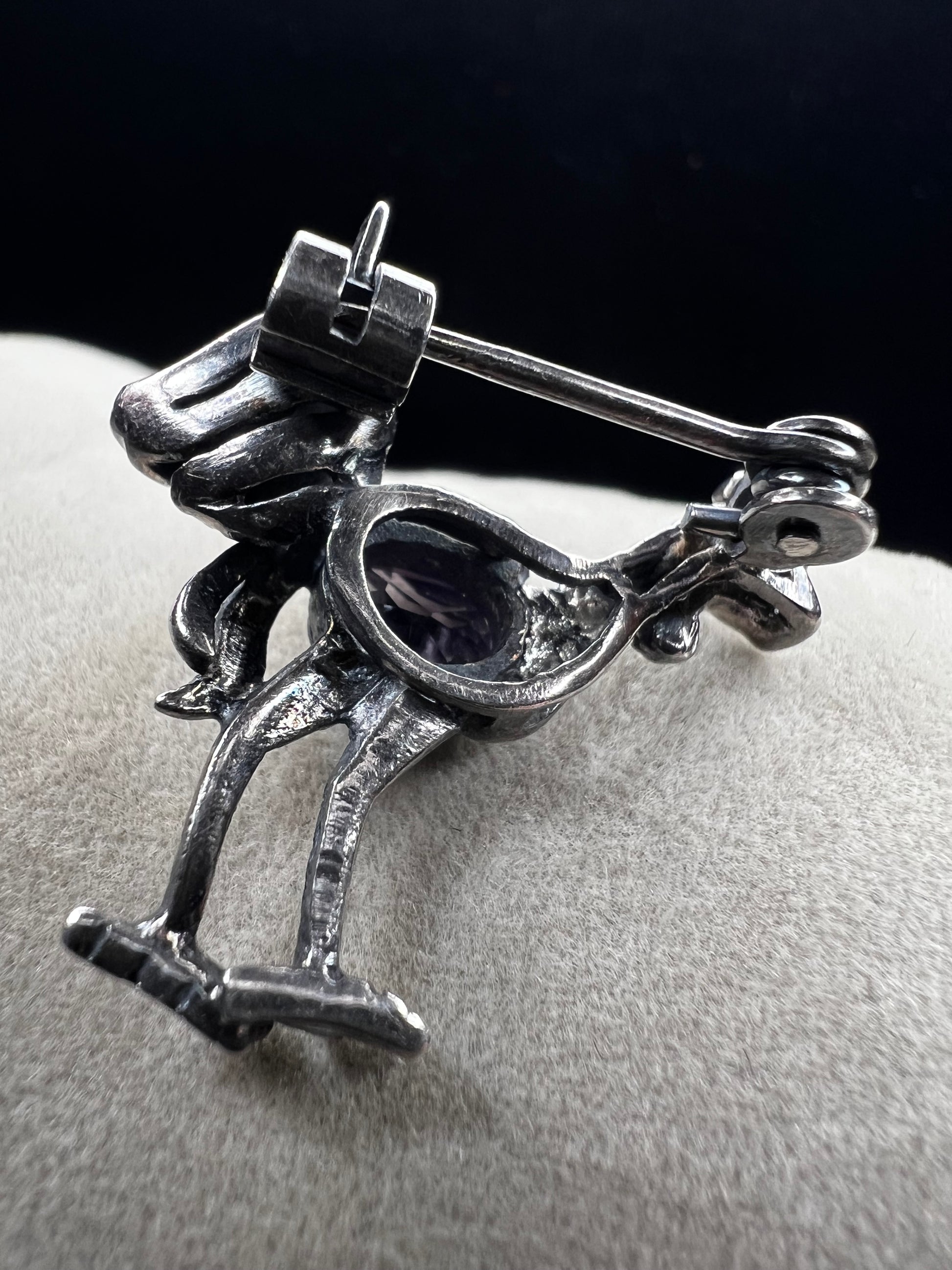 This is a striking mid-century rooster brooch that captures vintage elegance and whimsy. Handcrafted in sterling silver, this statement piece features a vibrant amethyst belly, accented with shimmering marcasite details that catch the light. Perfect for adding character to any outfit or displaying as a collectible treasure.