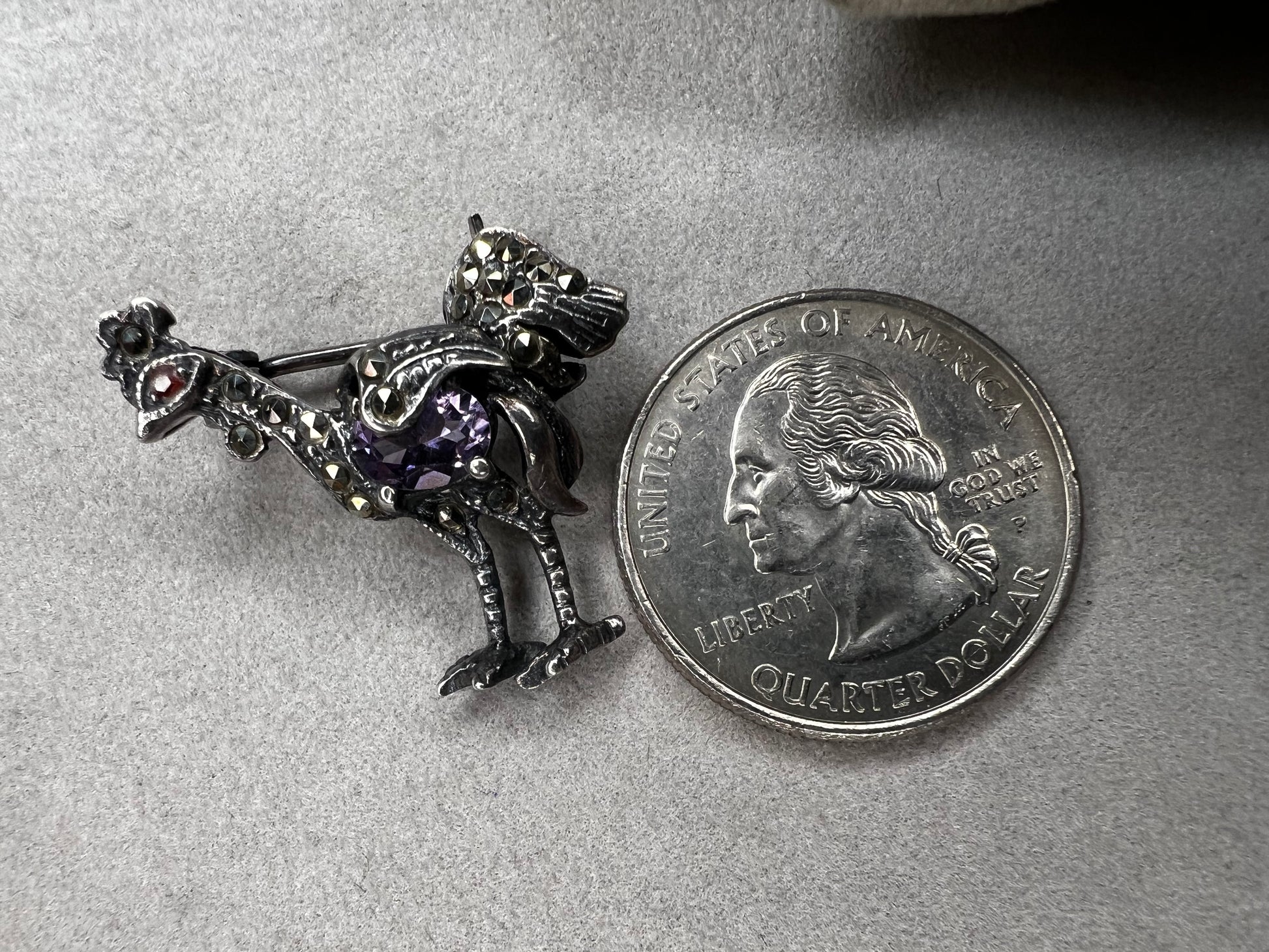 This is a striking mid-century rooster brooch that captures vintage elegance and whimsy. Handcrafted in sterling silver, this statement piece features a vibrant amethyst belly, accented with shimmering marcasite details that catch the light. Perfect for adding character to any outfit or displaying as a collectible treasure.