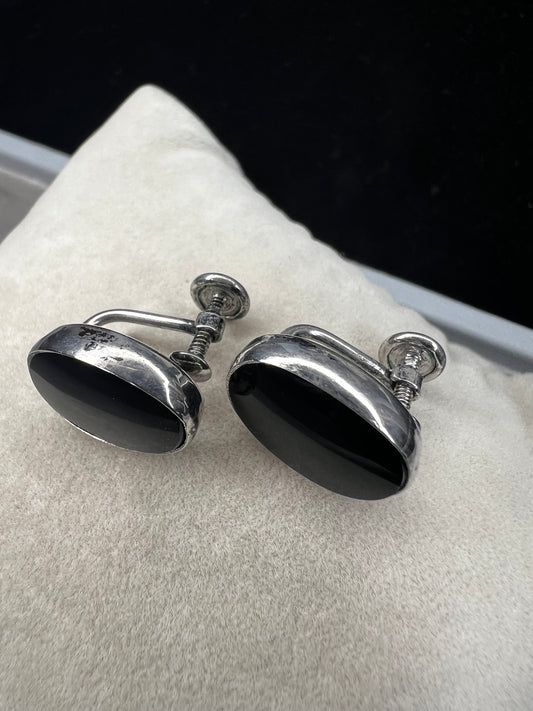 These vintage sterling silver screw-back earrings showcase an elegant oval jet stone, offering a timeless and sophisticated accessory. The secure screw-back design ensures comfortable wear without piercing, making them ideal for collectors and those seeking classic style with reliable functionality.
