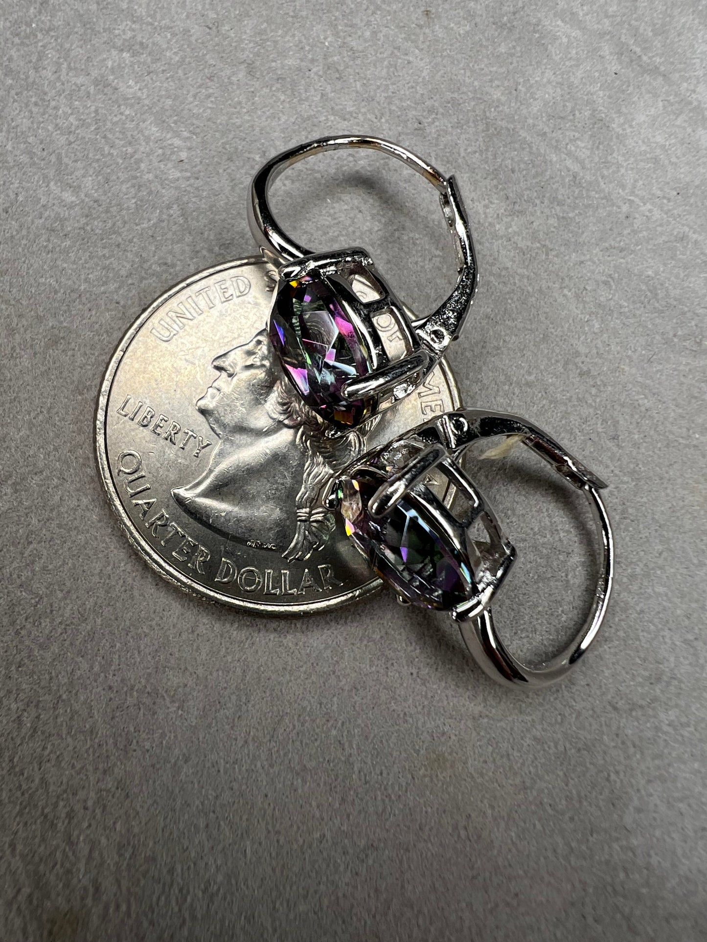 Elevate your everyday elegance with these stunning sterling silver mystic topaz earrings. Each piece showcases a radiant lab-created mystic topaz stone measuring 10 mm x 8 mm, displaying mesmerizing rainbow hues that catch the light beautifully. Crafted from genuine sterling silver, these earrings offer a perfect balance of sophistication and eye-catching sparkle.