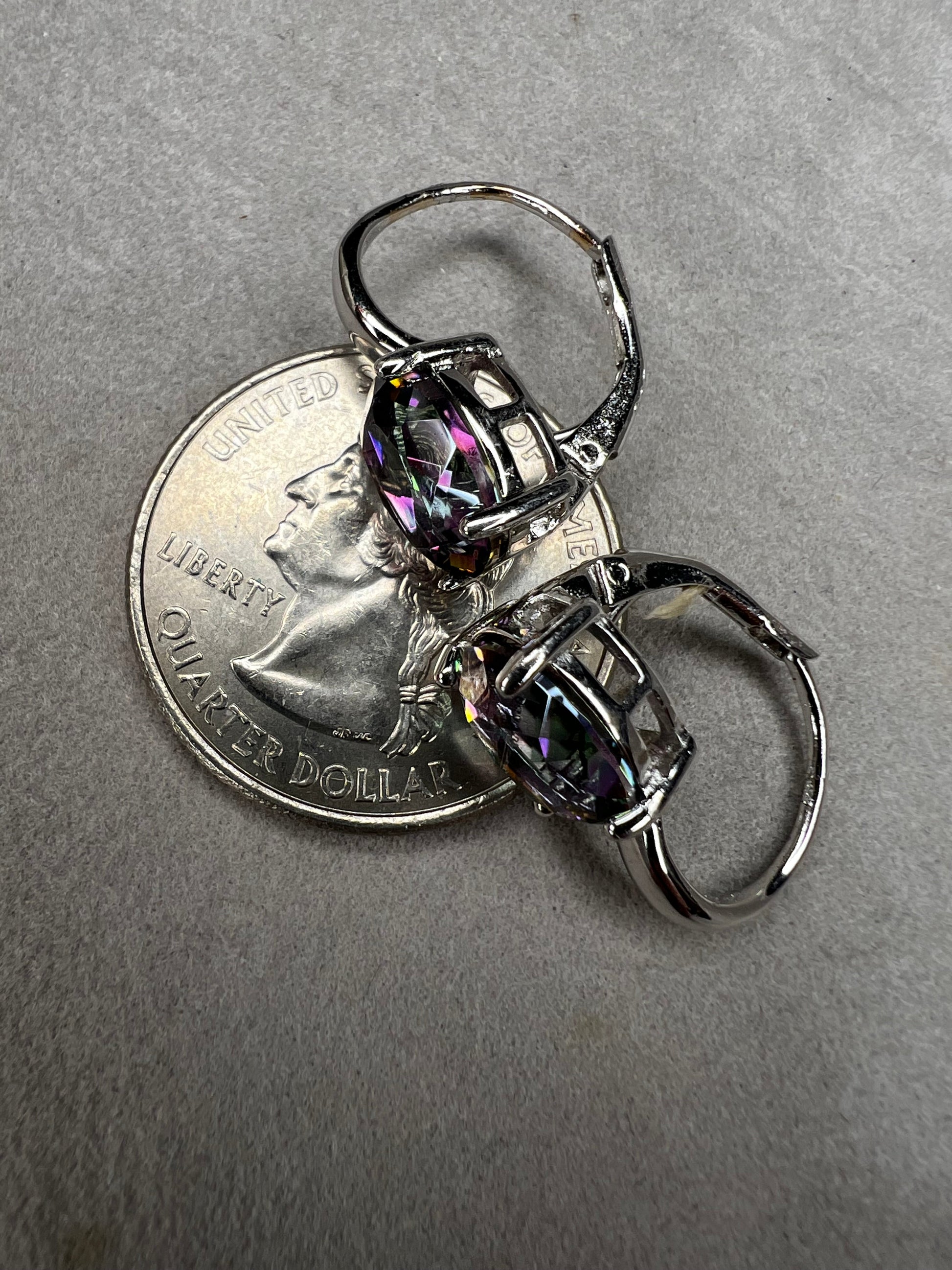 Elevate your everyday elegance with these stunning sterling silver mystic topaz earrings. Each piece showcases a radiant lab-created mystic topaz stone measuring 10 mm x 8 mm, displaying mesmerizing rainbow hues that catch the light beautifully. Crafted from genuine sterling silver, these earrings offer a perfect balance of sophistication and eye-catching sparkle.