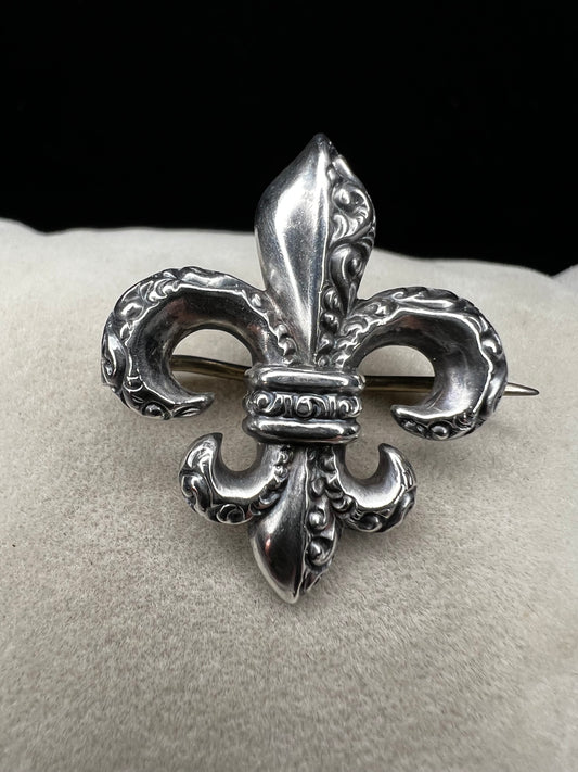 Elevate your vintage jewelry collection with this exquisite sterling silver Fleur De Lis brooch. Crafted with meticulous detail work, this timeless pin showcases the classic French symbol in sterling silver. Perfect for adding sophistication to any outfit or displaying as a treasured collectible.