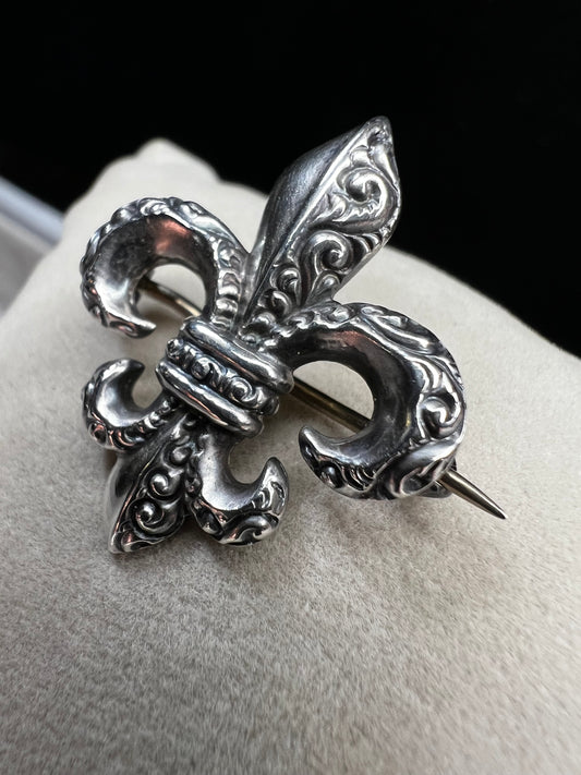 Elevate your vintage jewelry collection with this exquisite sterling silver Fleur De Lis brooch. Crafted with meticulous detail work, this timeless pin showcases the classic French symbol in sterling silver. Perfect for adding sophistication to any outfit or displaying as a treasured collectible.