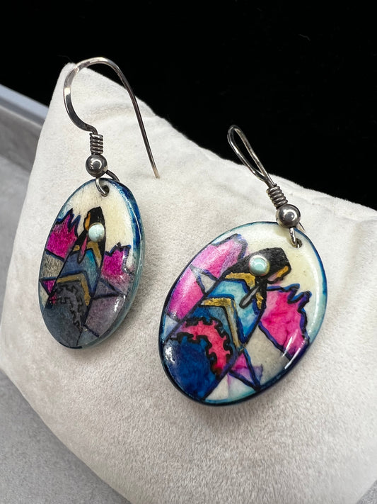 These vintage handmade earrings showcase a vibrant native scene on a lightweight material, expertly crafted to highlight intricate details and rich colors. They are completed with sterling silver hooks.