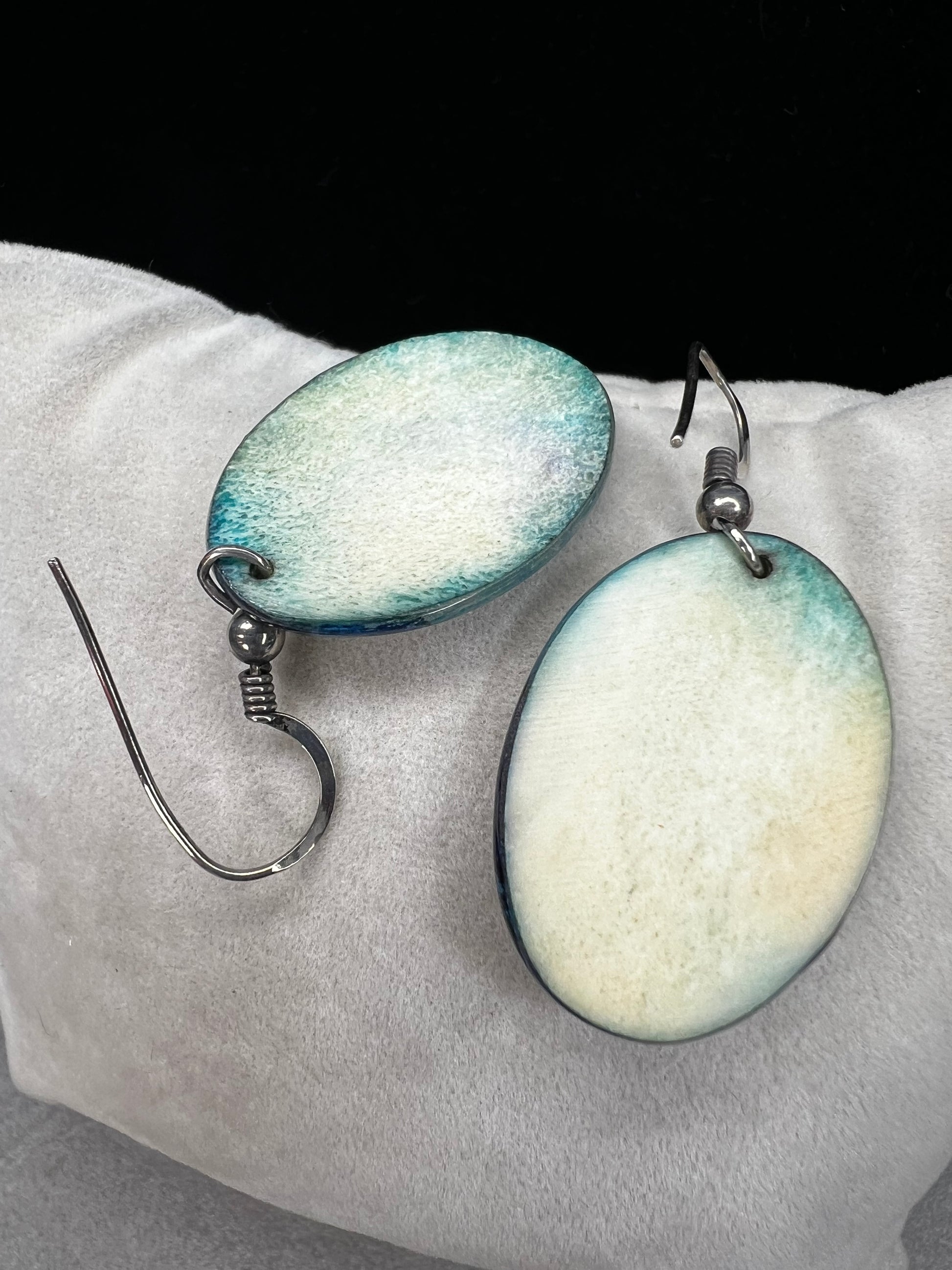 These vintage handmade earrings showcase a vibrant native scene on a lightweight material, expertly crafted to highlight intricate details and rich colors. They are completed with sterling silver hooks.