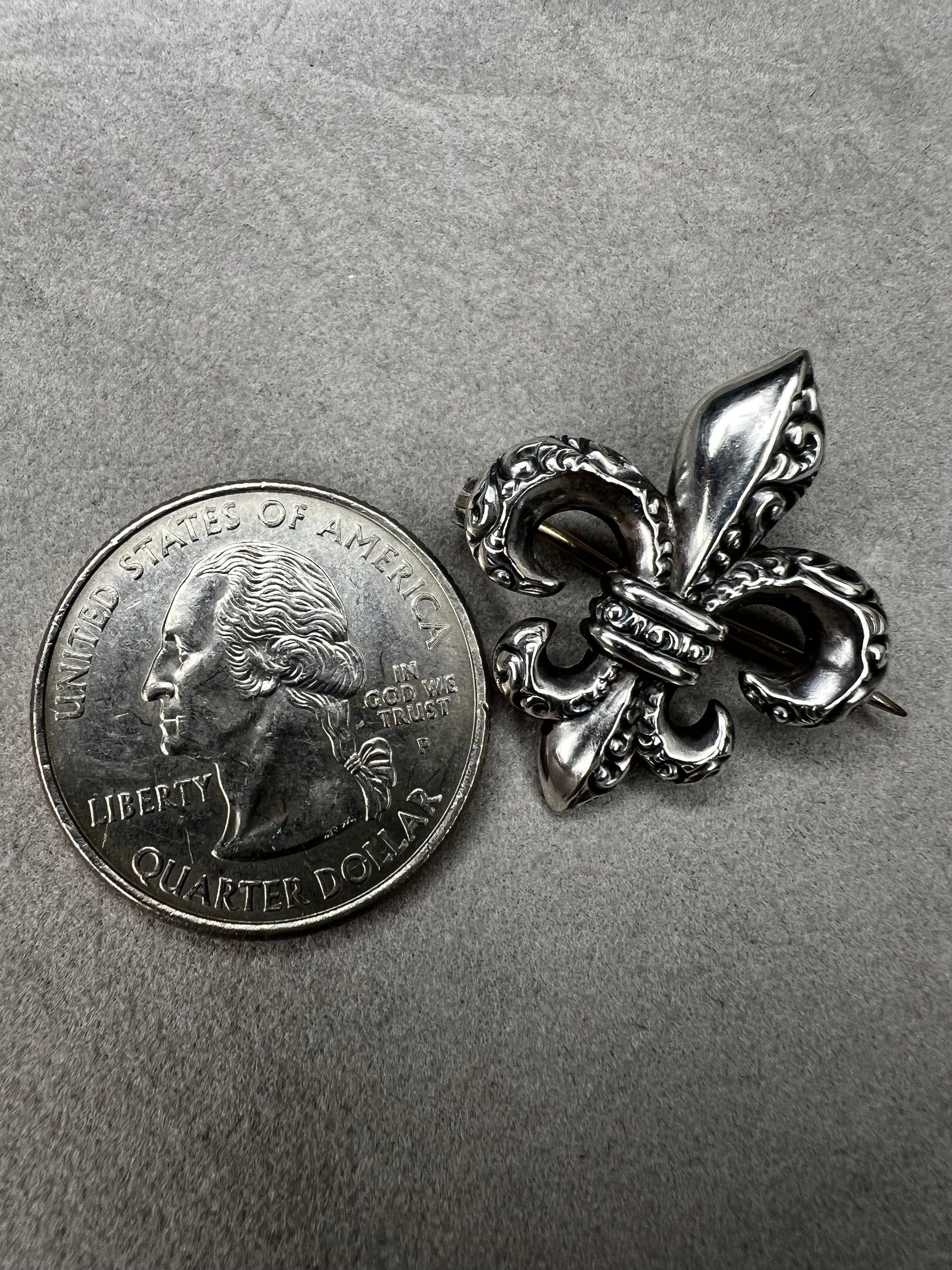 Elevate your vintage jewelry collection with this exquisite sterling silver Fleur De Lis brooch. Crafted with meticulous detail work, this timeless pin showcases the classic French symbol in sterling silver. Perfect for adding sophistication to any outfit or displaying as a treasured collectible.