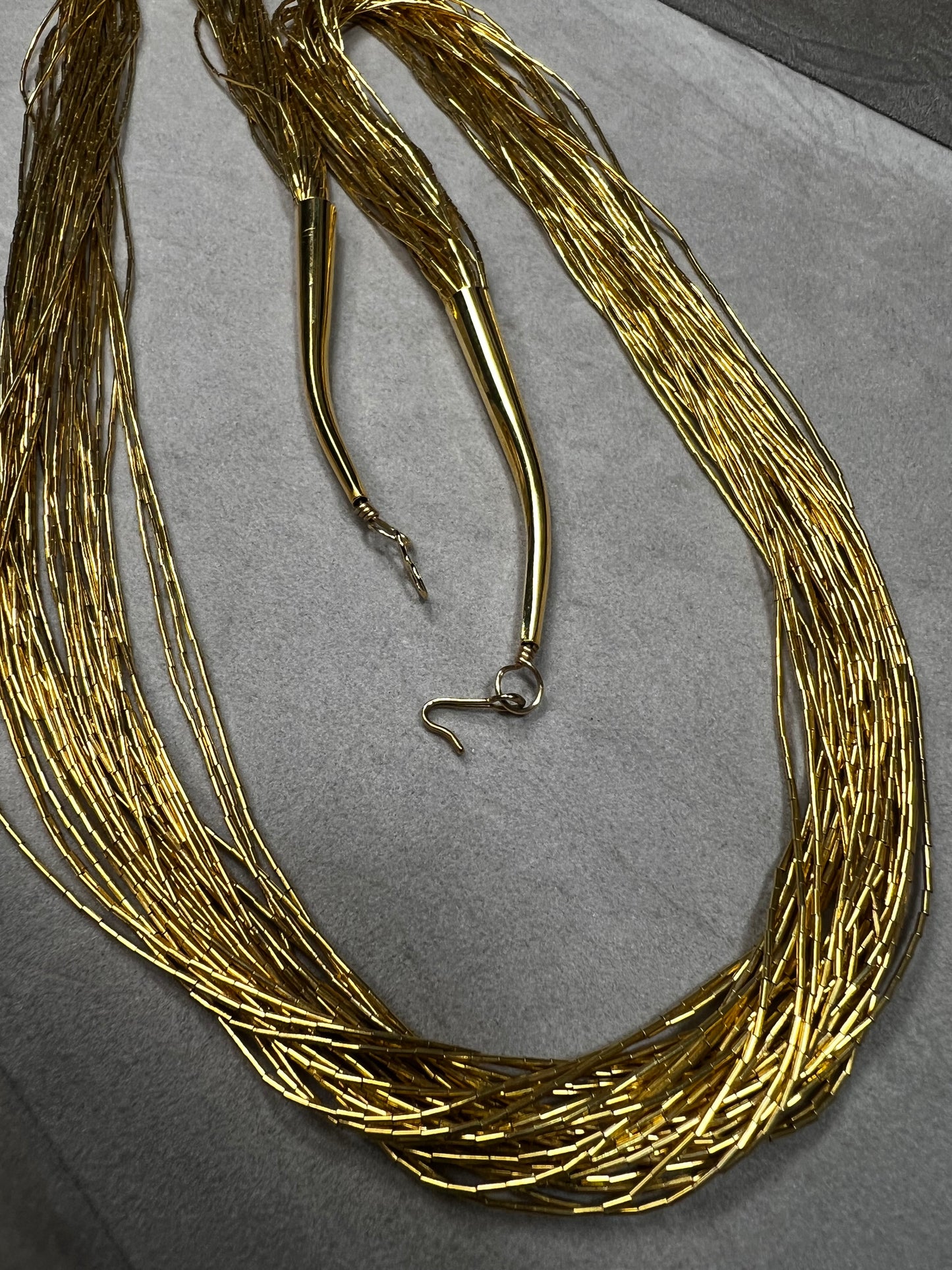 This is a striking gold over sterling silver necklace, featuring the iconic liquid-sterling design. The fluid, sculptural form creates visual movement and dimension, while the gold overlay adds warmth and luxury to the cool brilliance of sterling silver. With substantial length and thickness, this piece commands attention as a standalone statement.