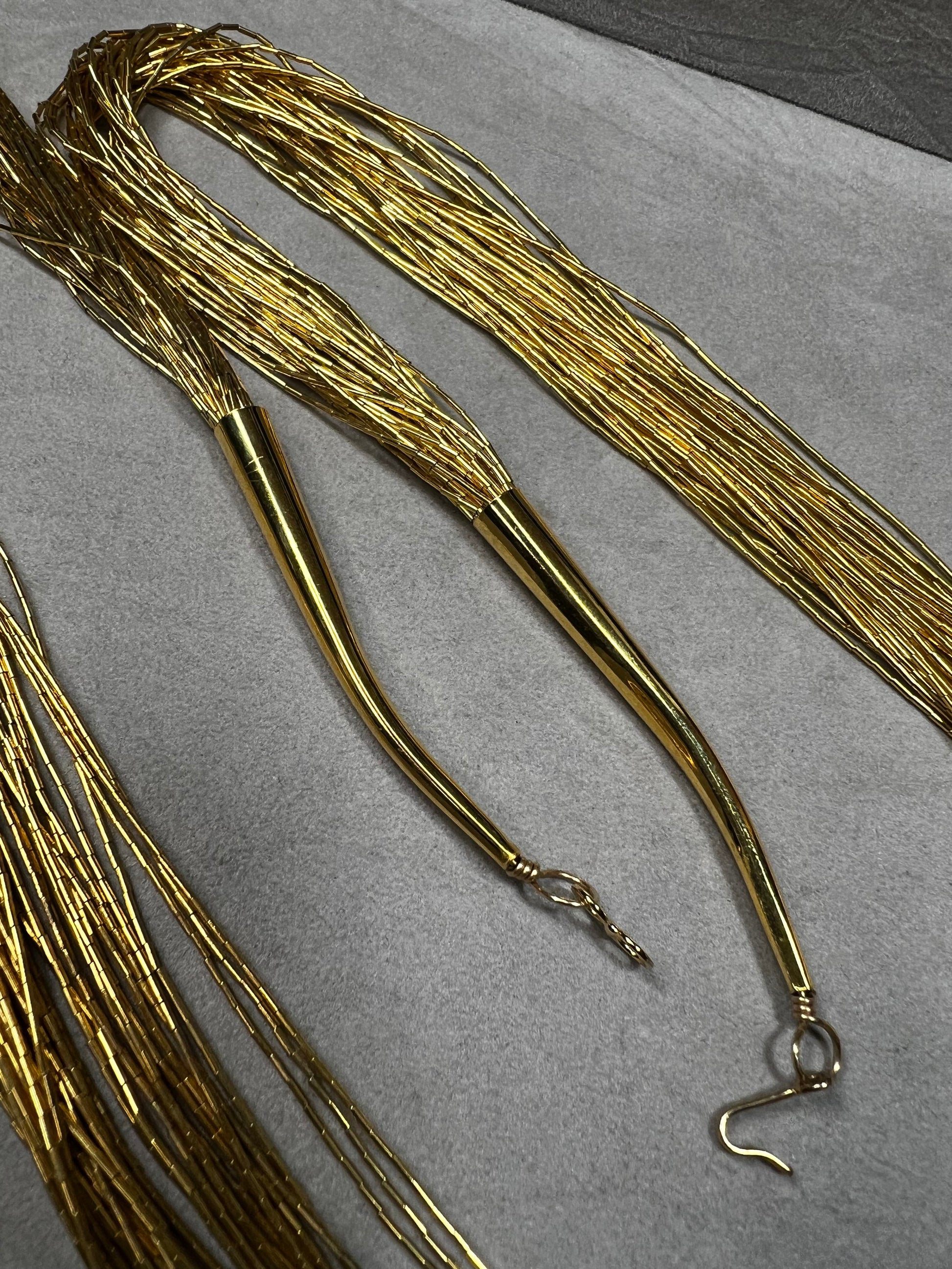 This is a striking gold over sterling silver necklace, featuring the iconic liquid-sterling design. The fluid, sculptural form creates visual movement and dimension, while the gold overlay adds warmth and luxury to the cool brilliance of sterling silver. With substantial length and thickness, this piece commands attention as a standalone statement.