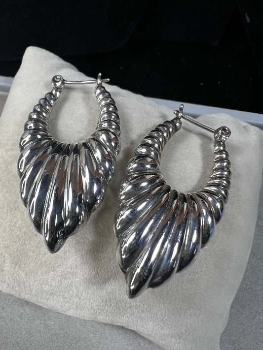 These vintage sterling silver scalloped shrimp hoop earrings are a distinctive accessory that complements any vintage-inspired ensemble. Ideal for collectors and enthusiasts seeking authentic vintage charm.