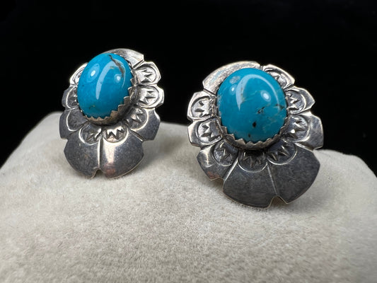 These sterling silver earrings showcase expertly crafted faux turquoise stones, set within intricately detailed silver settings. Signed LS.