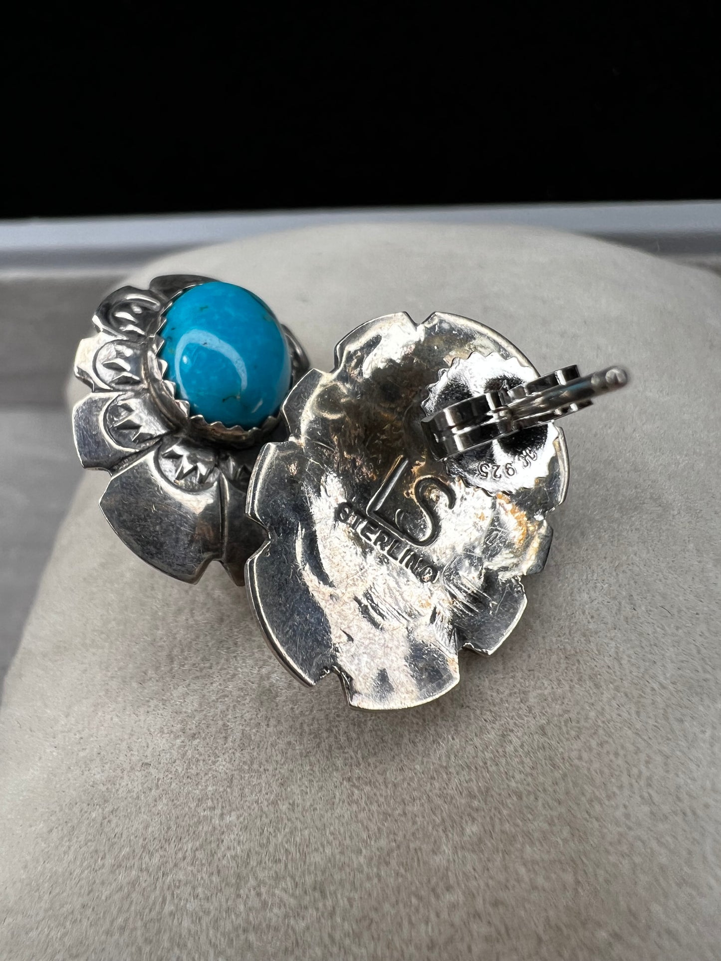 These sterling silver earrings showcase expertly crafted faux turquoise stones, set within intricately detailed silver settings. Signed LS.