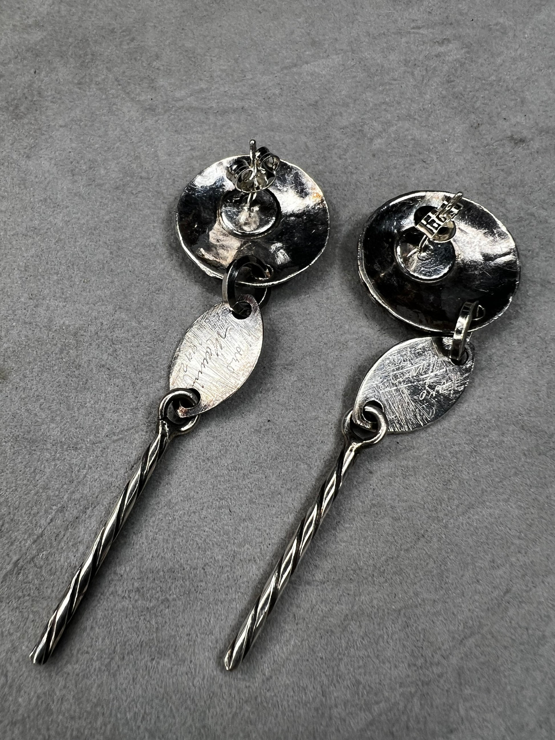 These sterling silver dangle earrings feature a distinctive 3-inch length and are signed by the designer, ensuring authenticity and exclusivity. Their elegant design complements both casual and formal attire.