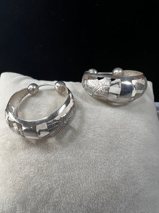 These vintage sterling silver hoop earrings showcase intricate cut-out silhouettes, blending classic design with artistic detail. Perfect for adding a subtle yet distinctive touch to any outfit.
