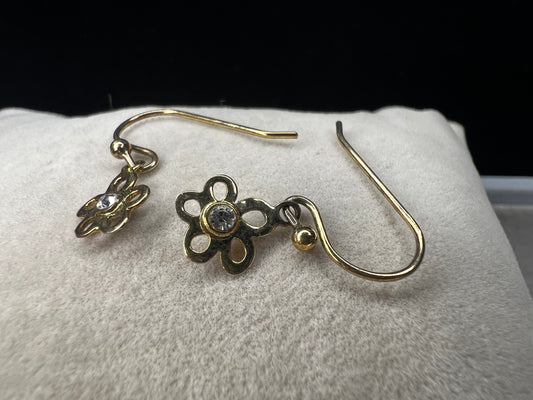 Crafted from sterling silver with a gold overlay, these earrings feature a small flower that hangs just below the ear.