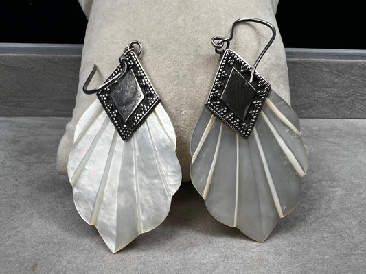 Crafted from sterling silver and mother of pearl, these vintage earrings measure about 3 inches long, making a bold and elegant statement.