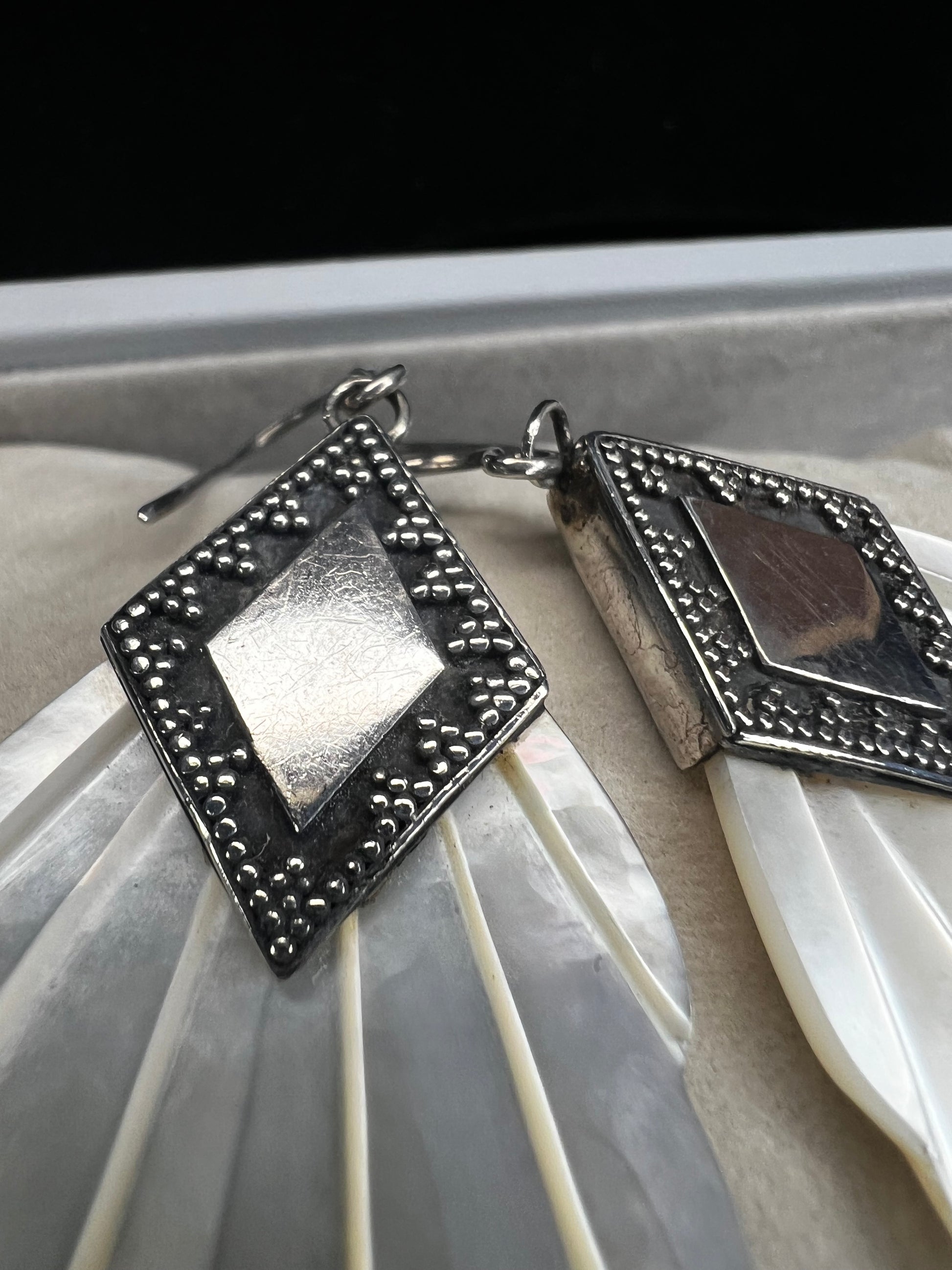 Crafted from sterling silver and mother of pearl, these vintage earrings measure about 3 inches long, making a bold and elegant statement.