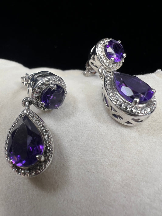 These sterling silver and amethyst drop earrings combine elegant design with quality craftsmanship. Perfect for adding a subtle pop of color to any outfit.