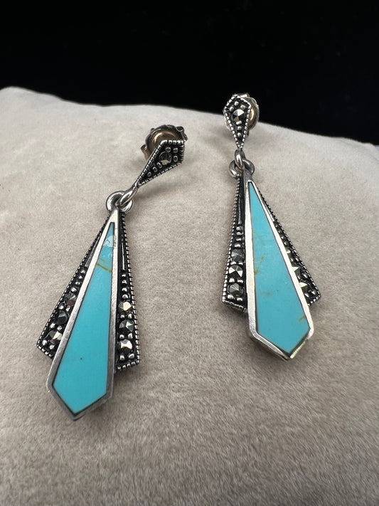These sterling silver dangle earrings combine the timeless elegance of marcasite with the vibrant appeal of faux turquoise. They are an ideal accessory for adding vintage-inspired sophistication to any outfit.