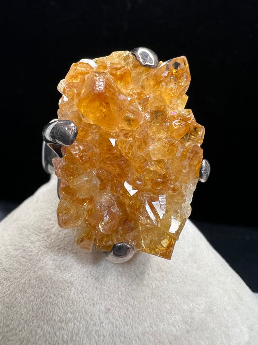 This sterling silver ring showcases a striking citrine specimen, expertly set to highlight its natural beauty. The warm, golden hues of the citrine contrast elegantly with the polished silver band, creating a sophisticated piece that commands attention.