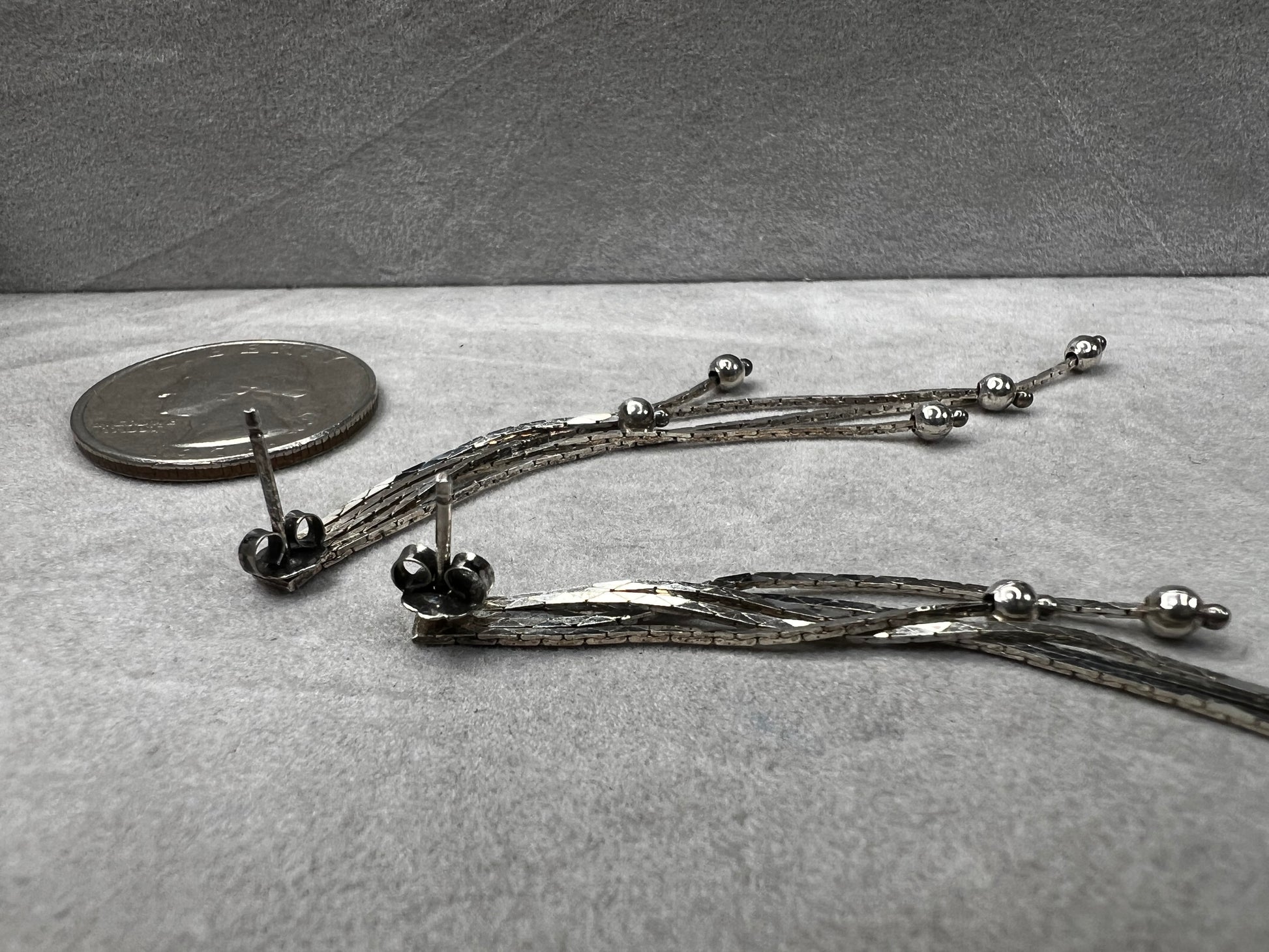 These sterling silver dangle earrings feature five chains of varying lengths, each adorned with a slide bead that moves gracefully with you. Their dynamic design adds elegant motion to your look, making them a charming accessory for any occasion.