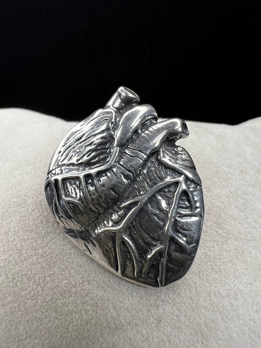 This sterling silver brooch, titled "Collision of Ideas," is expertly crafted to resemble a human heart. Its unique design combines artistic expression with fine craftsmanship.