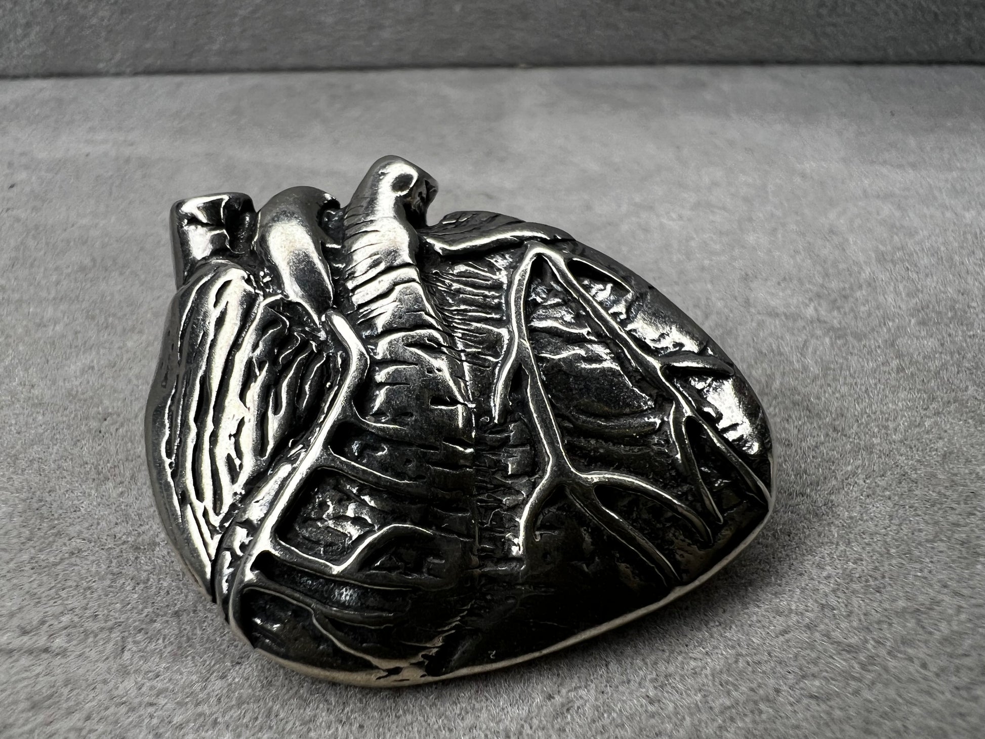 This sterling silver brooch, titled "Collision of Ideas," is expertly crafted to resemble a human heart. Its unique design combines artistic expression with fine craftsmanship.