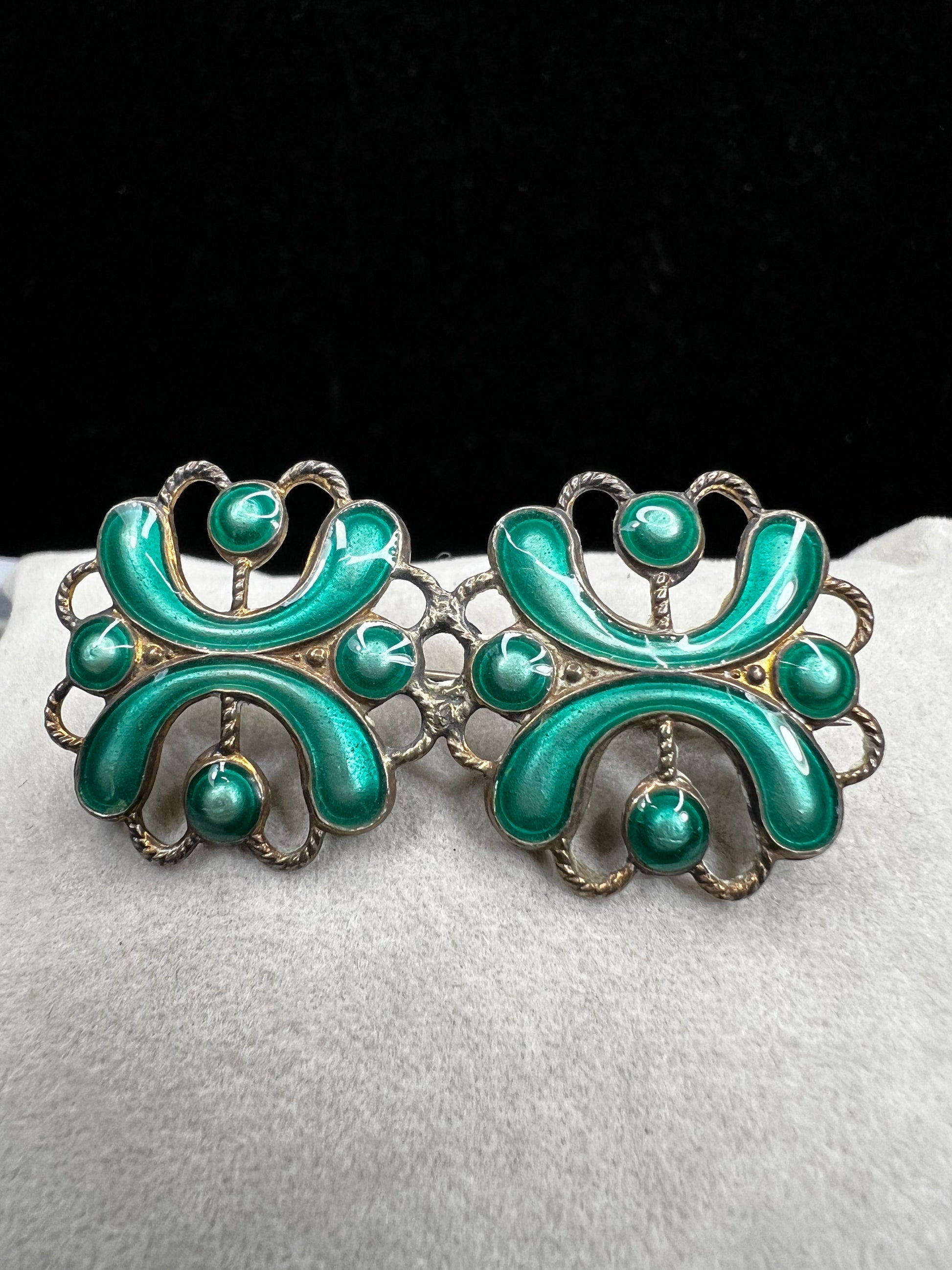This antique sterling silver brooch features a unique candy green enamel that captures attention with its vibrant charm. A distinctive piece from the turn of the 20th century, it offers a one-of-a-kind style that sets you apart in any room.