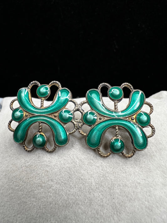 This antique sterling silver brooch features a unique candy green enamel that captures attention with its vibrant charm. A distinctive piece from the turn of the 20th century, it offers a one-of-a-kind style that sets you apart in any room.