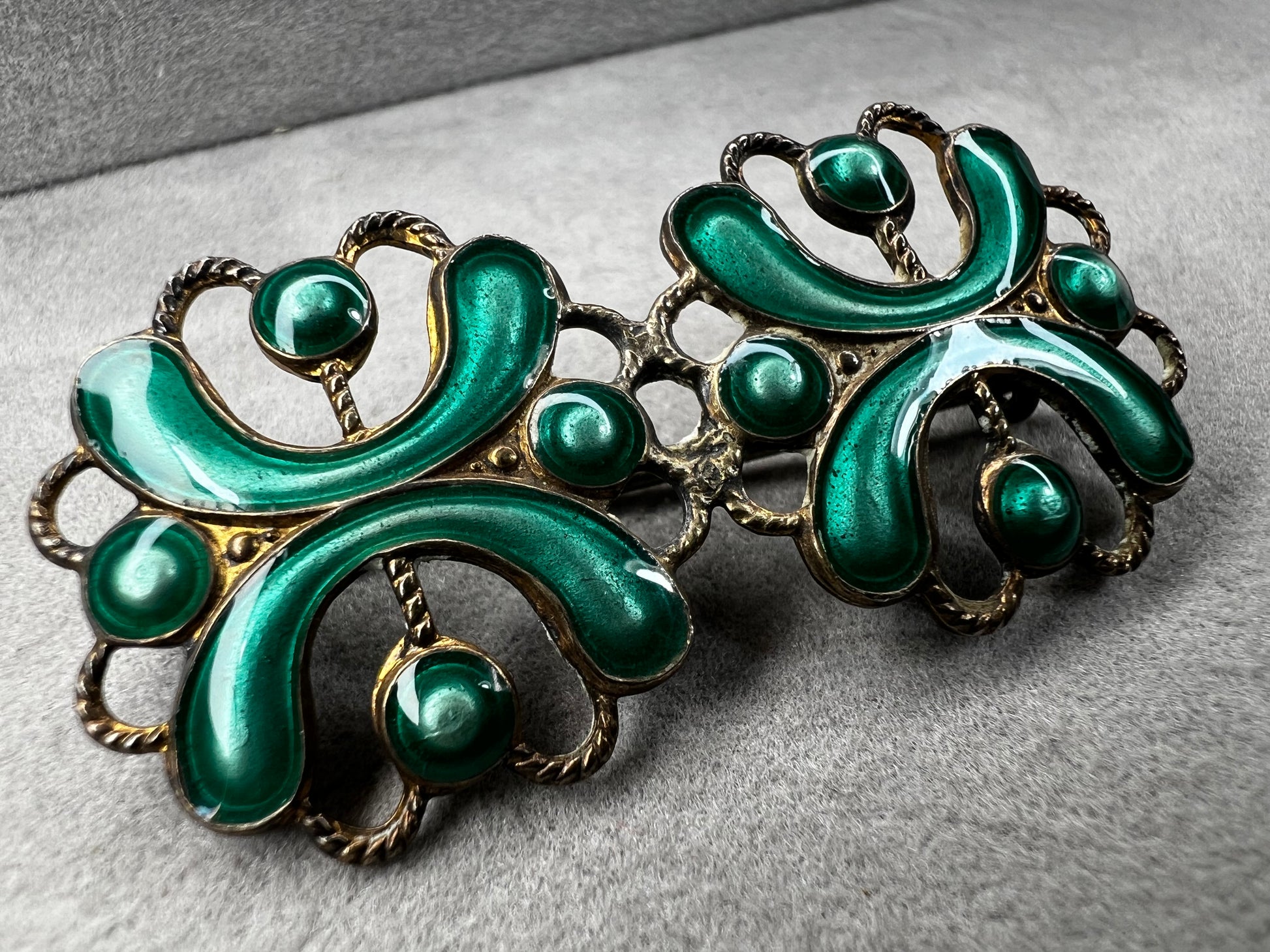 This antique sterling silver brooch features a unique candy green enamel that captures attention with its vibrant charm. A distinctive piece from the turn of the 20th century, it offers a one-of-a-kind style that sets you apart in any room.