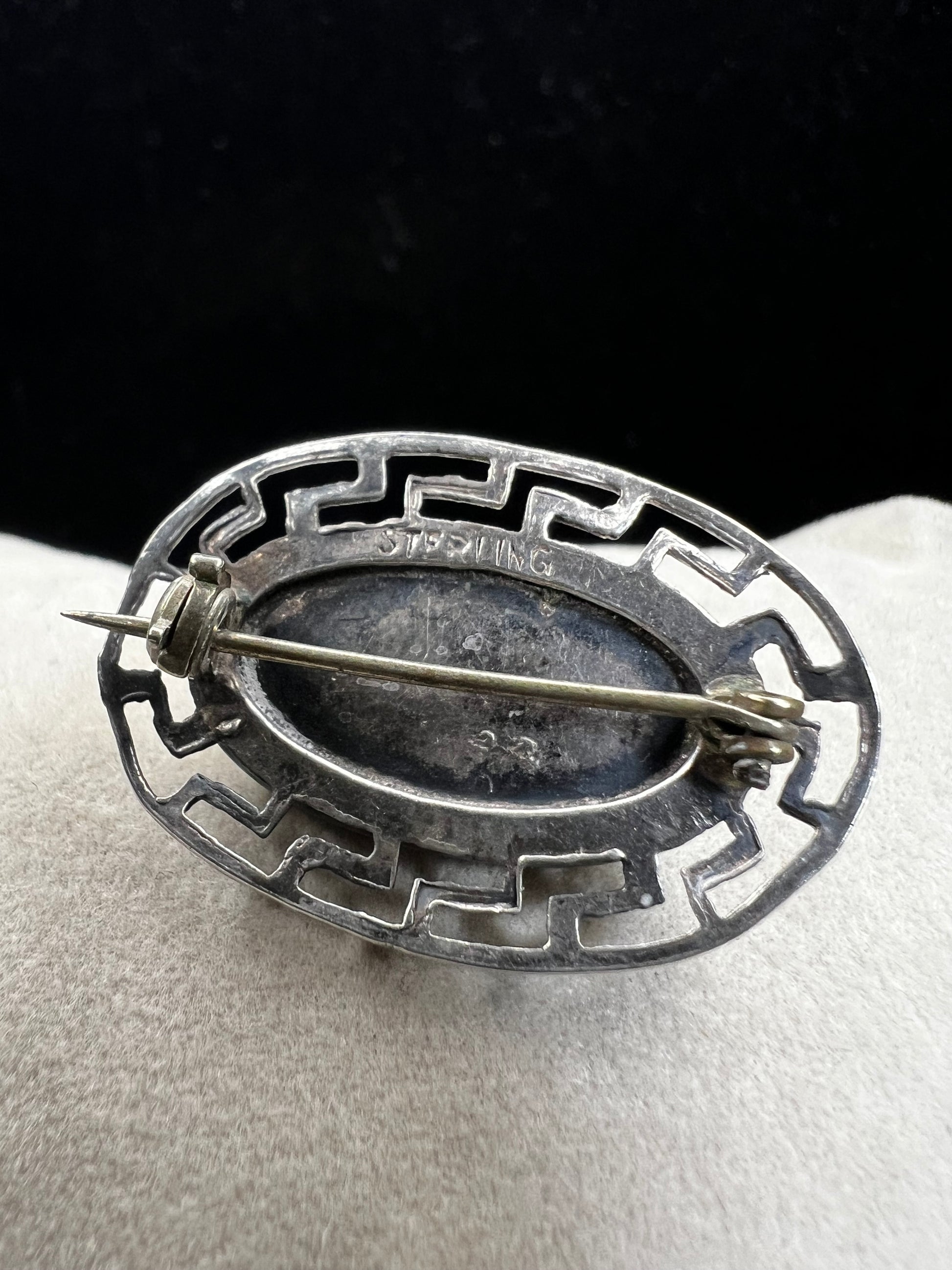 This vintage brooch showcases a tall abalone shell beautifully set within a sterling silver frame that features a classic Greek key design. Its elegant combination of natural iridescence and timeless pattern makes it a standout accessory that adds refined charm to any ensemble.