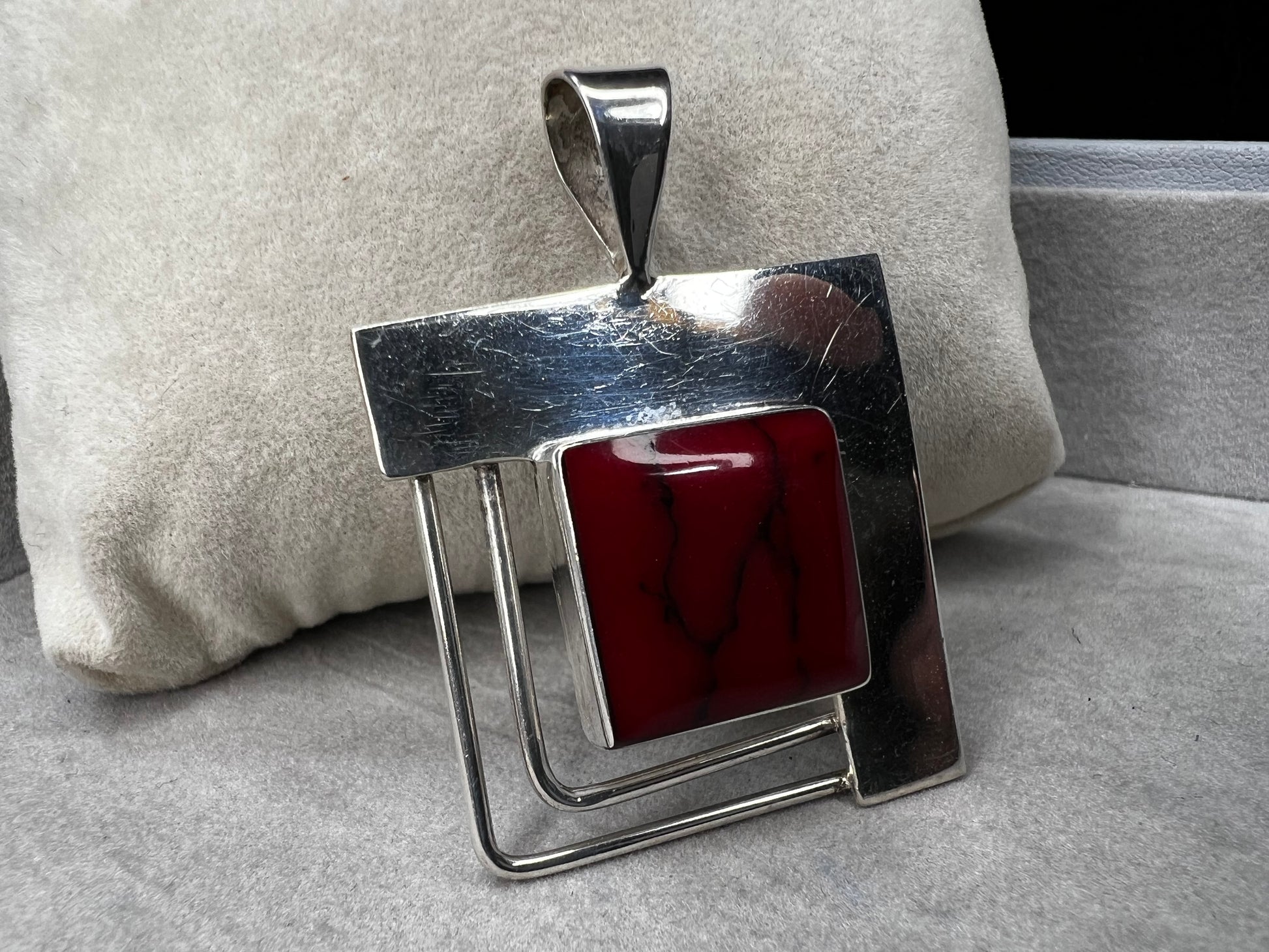 This striking sterling silver pendant features a bold blood red faux stone, designed to stand out beautifully with larger silver chains. Handcrafted in Mexico, it combines unique artistry with timeless elegance, making it a perfect statement piece to complement your collection.