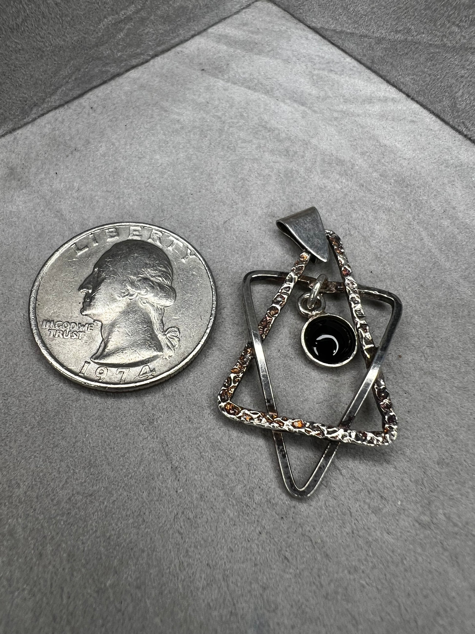 Crafted from sterling silver and marked Israel, this Star of David pendant features a striking jet cabochon delicately suspended in the center. Its thoughtful design combines tradition with elegance, making it a meaningful accessory that supports your personal expression of faith.