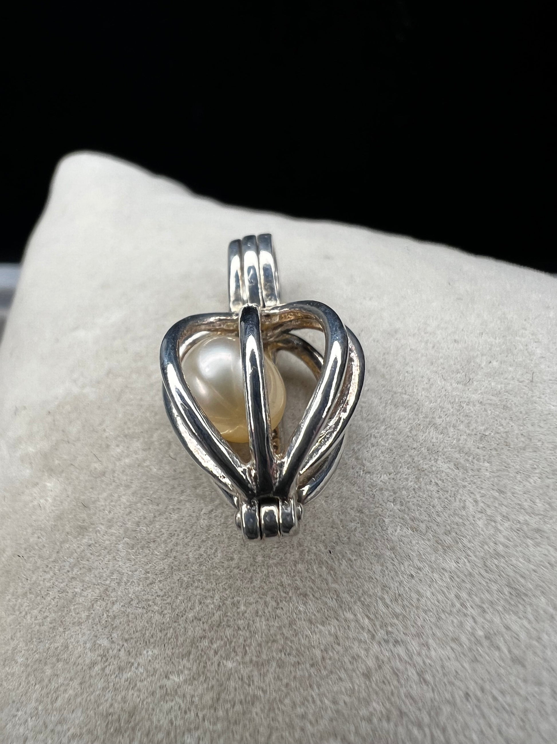 This sterling silver cage pendant features a natural pearl inside and opens up for a unique touch. it can be worn as a pendant or charm, offering a delicate and elegant addition to your jewelry collection. Signed LUC.