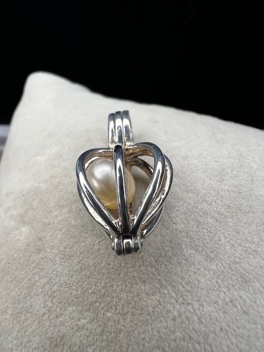 This sterling silver cage pendant features a natural pearl inside and opens up for a unique touch. it can be worn as a pendant or charm, offering a delicate and elegant addition to your jewelry collection. Signed LUC.