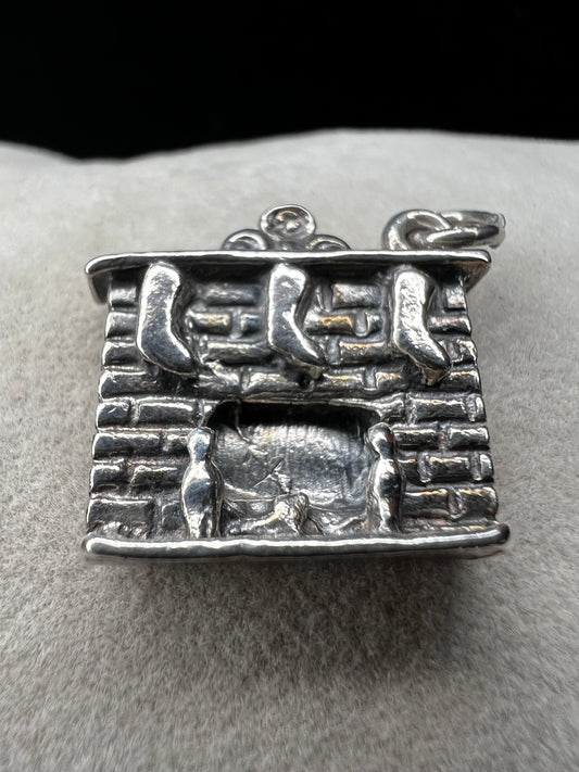 This Danecraft sterling silver charm captures the cozy holiday spirit with stockings hanging from the mantle above a wood-burning fire. It’s a charming addition to your Christmas collection, perfect for celebrating festive traditions and adding warmth to your jewelry.